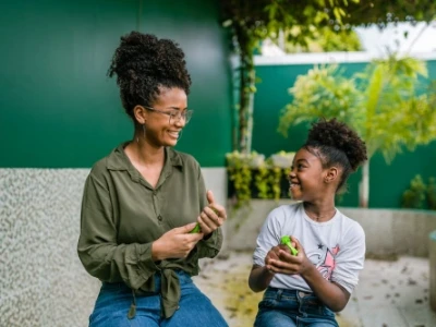 Mãe e filha sorridentes brincando no quintal