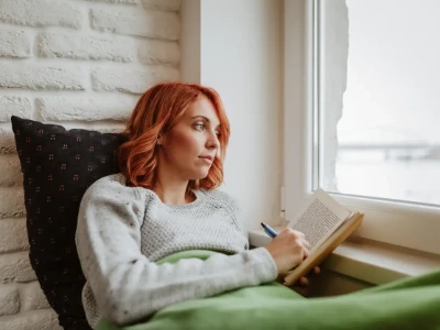 Garota sentada na cama segurando e sublinhando livro