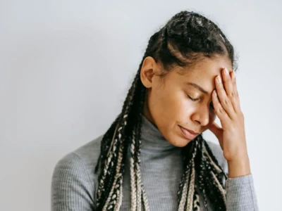 Mulher encostando a mão na testa devido a dor de cabeça.
