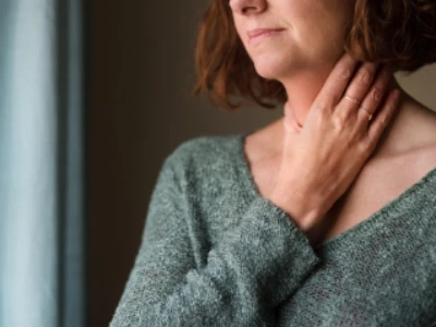 Mulher com blusa de manga comprida e mão na garganta