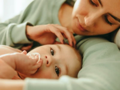 Mão deitada junto a bebê acariciando a cabeça da criança