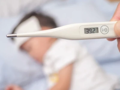 A pessoa segura um termômetro onde é indicada uma alta temperatura relacionada à febre. Ao fundo, vê-se uma criança convalescente, sugerindo ser quem relatou essa alta temperatura, sofrendo de febre e mal-estar.