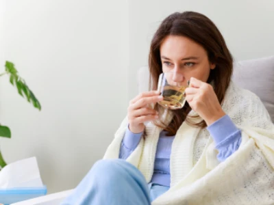 Mulher agasalhada sentada em poltrona tomando chá