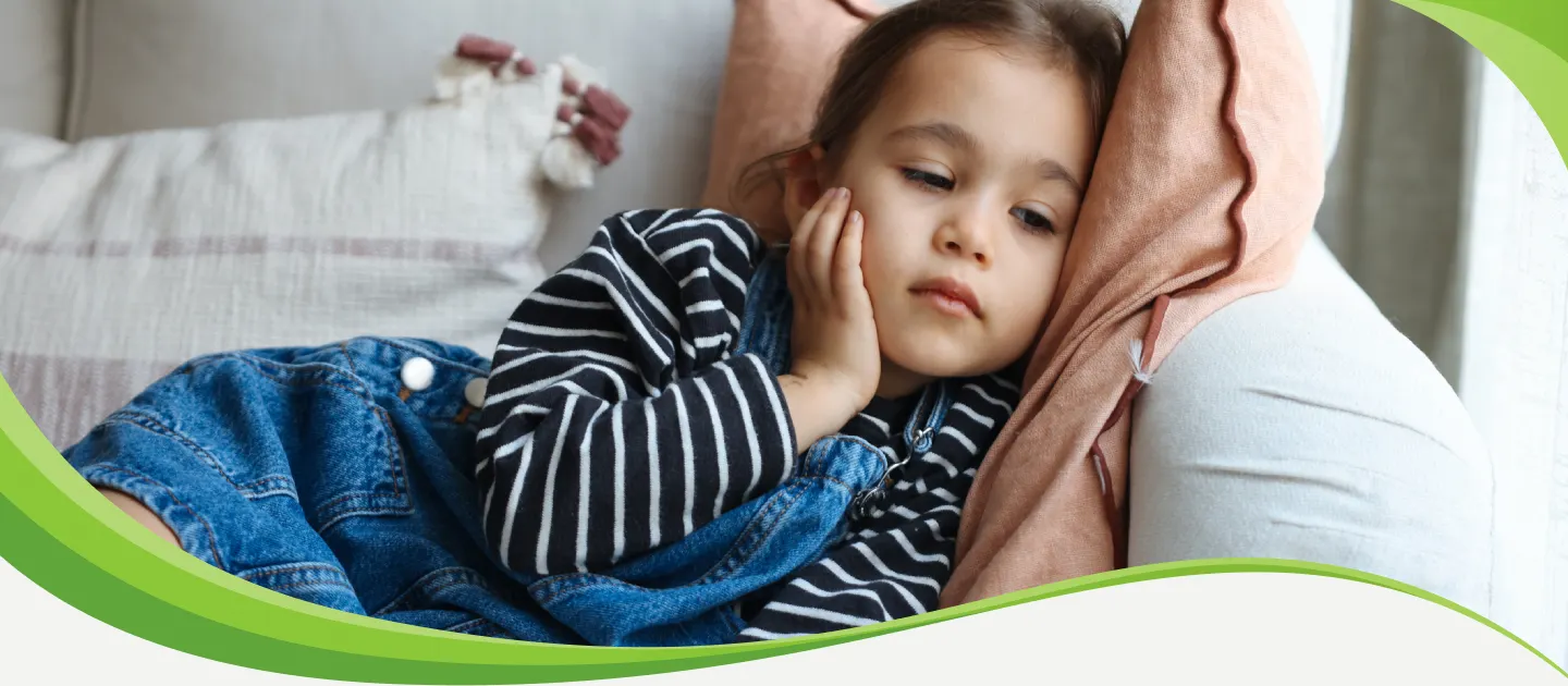 Menina deitada de lado no sofá, com a mão no rosto e expressão cansada.