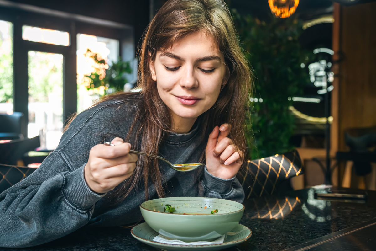 Mulher agasalhada tomando sopa em restaurante