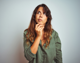 Mulher com a mão no queixo e olhar questionador