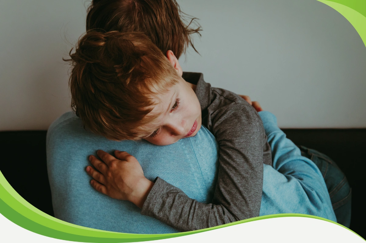 Garoto sendo acolhido por adulto, abraçado e com a cabeça em seu ombro, parece ter chorado.