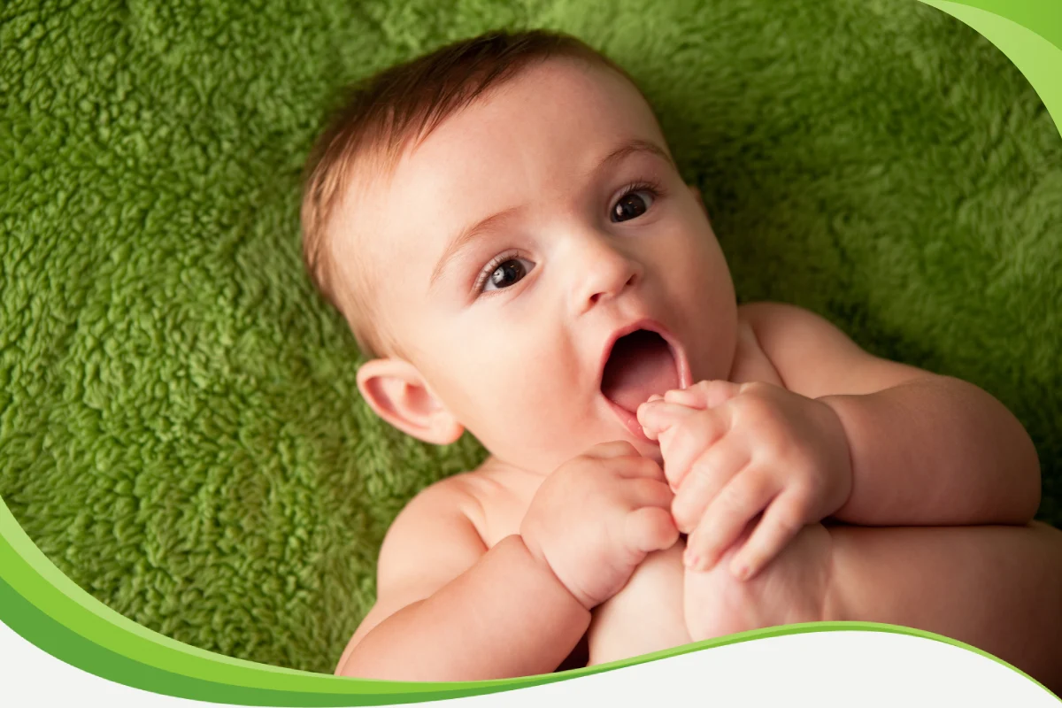 Bebê pequeno e feliz levando o pezinho à boca